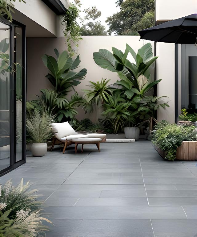 Patio con piso cerámico gris mate, mesa baja y vegetación alrededor de una galería de casa amplia